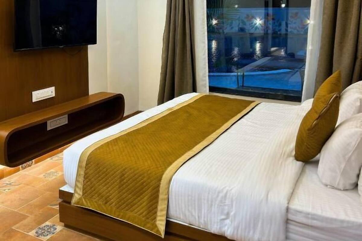 Habitación de hotel con cama, televisión, ventilador de techo y vista a una piscina.