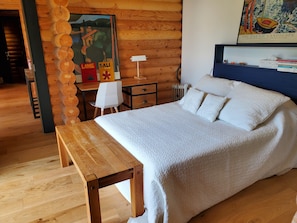 Un intérieur en bois avec un lit, un bureau et une affiche accrochée au mur.