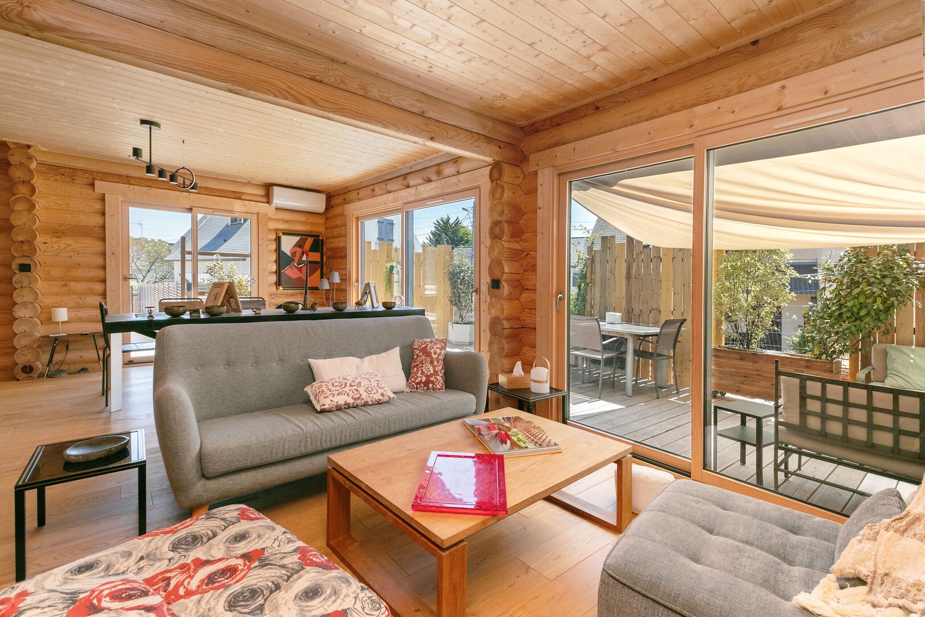 A log cabin interior with a sofa, coffee table, and dining area.