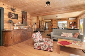 Ein gemütliches Blockhaus-Interieur mit Holzausbau, einer Couch, einem Couchtisch und einem Essbereich.