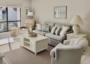 A living room with a sofa, armchairs, a coffee table, and a lamp. - Runaway Bay 258 - Beach, Bay, Pool, Pickleball (Bradenton Beach)