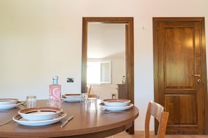 A dining table set with plates, bowls, glasses, and cutlery, a chair, and a wooden door. - Cucca's Home - Three Bedroom Apartment, Sleeps 5 (Siniscola)