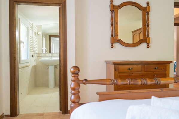 A bedroom with a wooden bed frame, a wooden dresser, and a mirror on the wall. - Cucca's Home - Three Bedroom Apartment, Sleeps 5 (Siniscola)