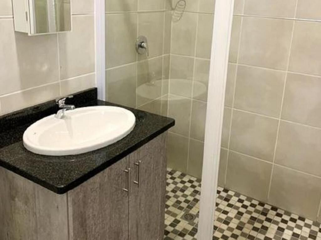 A bathroom with a sink, mirror, and shower.
