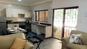 A compact living space with a kitchenette, dining area, and two sofas. - Spacious 2-bedroom Apartment With Garden View in Hartbeespoort (Hartbeespoort)
