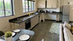 A modern kitchen with a dining area, featuring a sink, stove, and cabinets. - Spacious 2-bedroom Apartment With Garden View in Hartbeespoort (Hartbeespoort)
