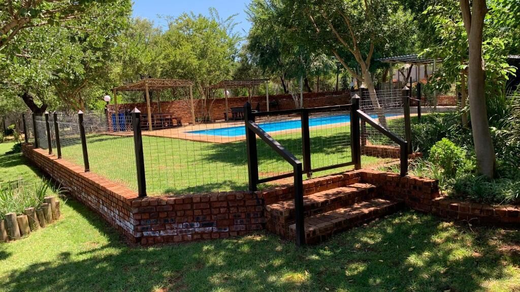 A backyard with a swimming pool, brick steps, and a fenced area.