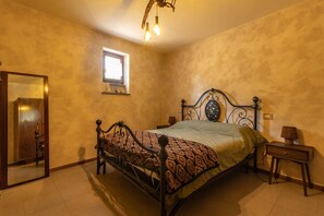Ein Schlafzimmer mit Bett, Nachttisch, Spiegel und Fenster.
