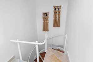 A white metal staircase with a handrail, leading to a landing with a white wall and a wooden floor. - Beachfront Penthouse | Electricity Included (Punta Cana)