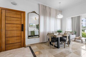 Un comedor moderno con puerta de madera, un espejo grande y una mesa de comedor con sillas.