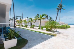 A beachfront property with a pool, palm trees, and a clear sky. - Beachfront Penthouse | Electricity Included (Punta Cana)