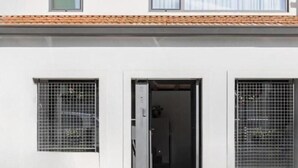 A building with a white facade, a tiled roof, and two windows with metal grilles. - URBAN LOFT PORTO (Porto)