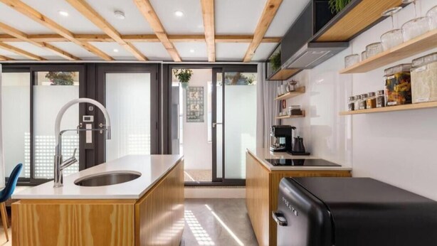 A modern kitchen with a wooden island, a black refrigerator, and a coffee machine. - URBAN LOFT PORTO (Porto)