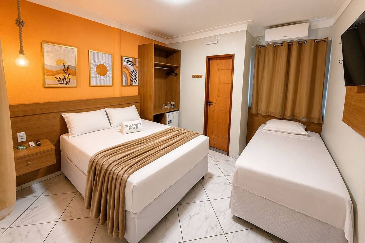 A hotel room with a large bed, a smaller bed, a wardrobe, a nightstand, a lamp, and artwork on the wall.