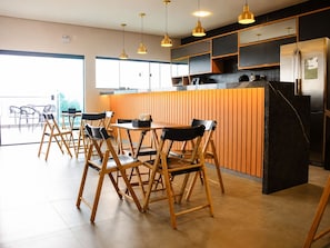 Una cocina moderna con una isla central, sillas de madera e iluminación colgante.