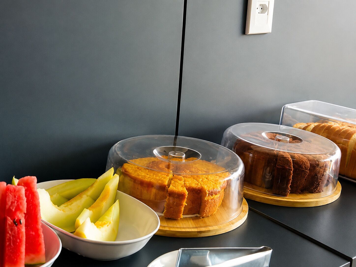 Un bufé con diversos alimentos, incluyendo un pastel, pan y fruta.