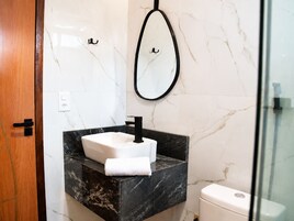 Un baño con lavamanos de mármol, un espejo y un inodoro.