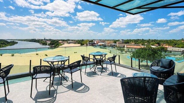 Una terraza con mobiliario exterior, vistas a un río y una piscina.