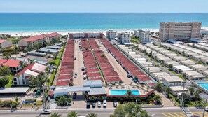 Ein Hotel mit einer langen Reihung von Zimmern, einem Pool und Blick auf den Strand.