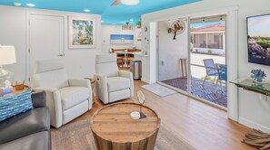 A modern living room with a sofa, armchairs, a coffee table, and a TV.