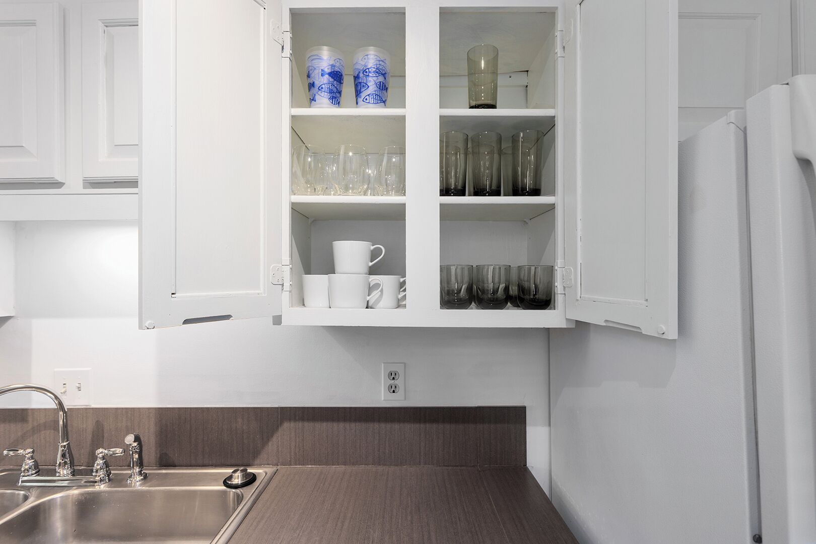 A kitchen with a built-in cabinet containing glassware and cups.