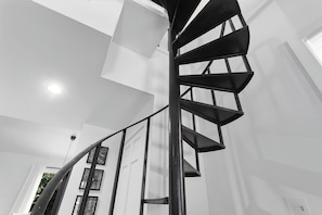 Una scala a chiocciola dal design moderno, pareti bianche e una lampada a soffitto.