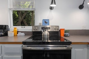 Una cucina con fornello, forno e una finestra con persiane.
