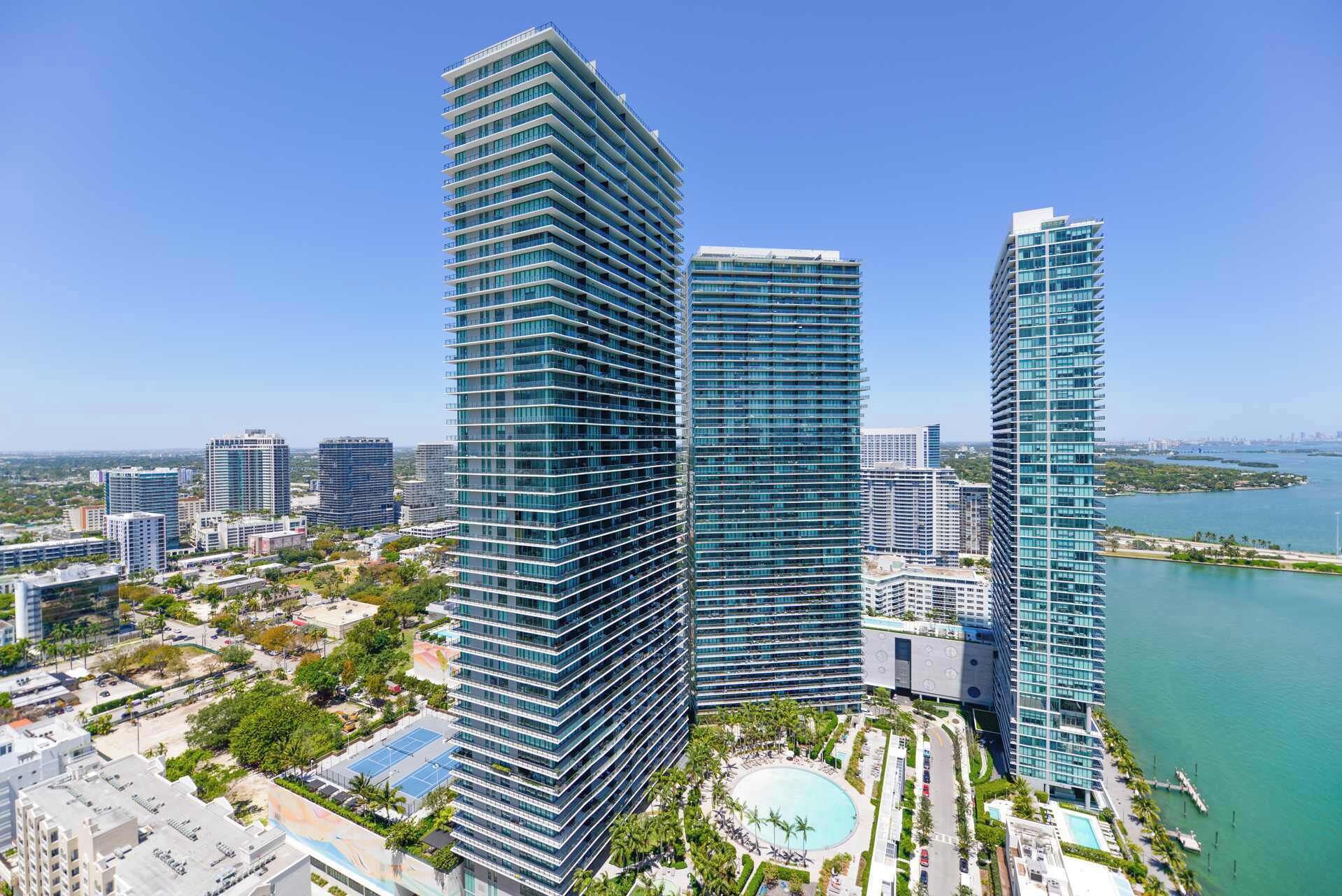 A high-rise hotel with a modern design, featuring multiple balconies and a central courtyard with a pool.