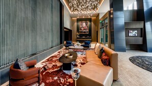 Un intérieur moderne avec un canapé, des fauteuils, une table basse, un lustre et un téléviseur.