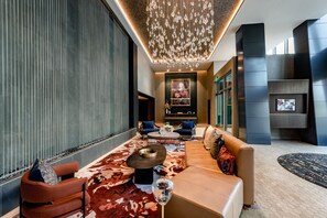 A modern interior with a sofa, chairs, a coffee table, a chandelier, and a TV. - Modern Apt Near DC & Metro | Pool & Gym (Arlington)