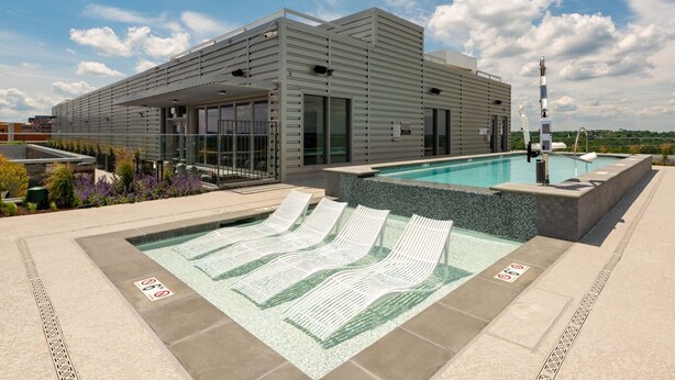 Un bâtiment moderne doté d’un espace piscine comprenant des chaises longues et un jacuzzi.