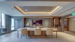 Une cuisine moderne dotée d’un îlot central, de meubles encastrés et d’un grand téléviseur à écran plat.