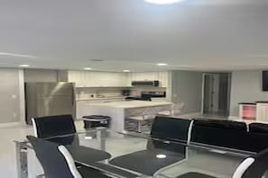 A modern kitchen with stainless steel appliances, a glass dining table, and black chairs. - Cozy 2-bedroom house in charming Port Richey with AC (Port Richey)