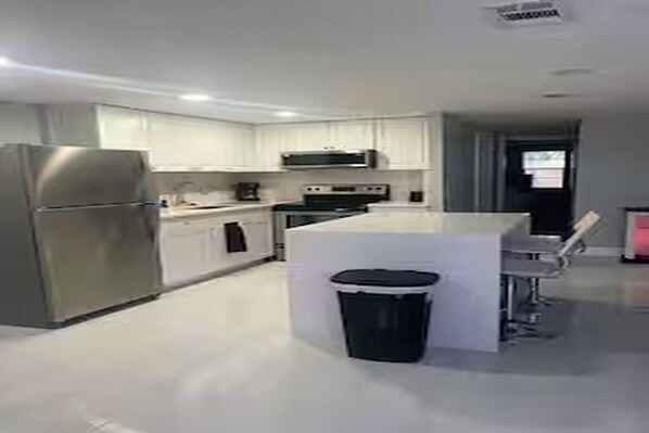 A modern kitchen with white cabinets, stainless steel appliances, and a central island. - Cozy 2-bedroom house in charming Port Richey with AC (Port Richey)