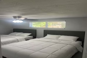 A bedroom with two beds, a ceiling fan, and a window with a view. - Cozy 2-bedroom house in charming Port Richey with AC (Port Richey)