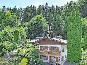 Ein zweistöckiges Gebäude mit Balkon, umgeben von Bäumen und einem bewaldeten Gebiet.