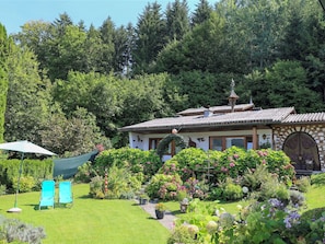 Ein Haus mit Garten, einem Pavillon und zwei Liegestühlen.