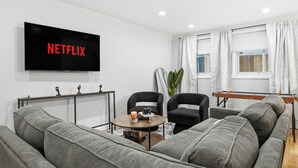 Een moderne woonkamer met een flatscreen televisie, grijze banken, een salontafel en een futon.
