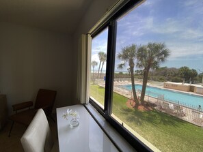 Ein Zimmer mit großem Fenster mit Blick auf einen Pool und Palmen.