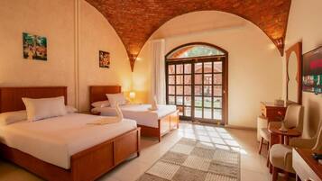 Una camera d'albergo con soffitto in mattoni, un'ampia finestra ad arco, un letto, una scrivania e una televisione.