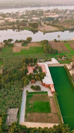 Vista aérea de una zona rural con campos, una masa de agua y un edificio con techo verde.