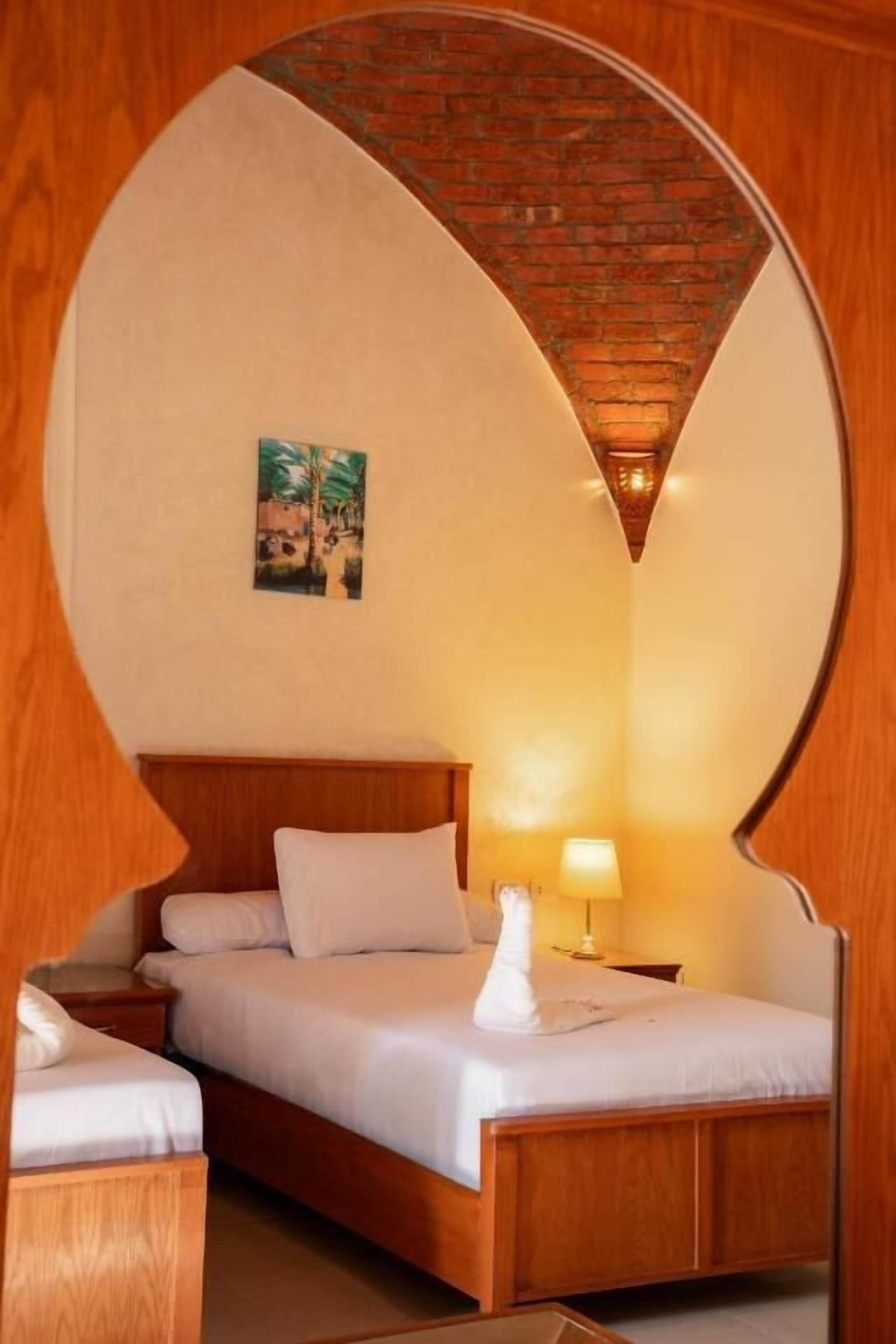 A hotel room with a wooden bed, a nightstand, a lamp, and a picture on the wall.