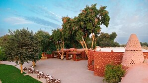 Un patio con mobiliario exterior, una construcción de ladrillo y árboles.