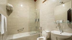 Un baño moderno con ducha de vidrio, bañera, inodoro y lavamanos.