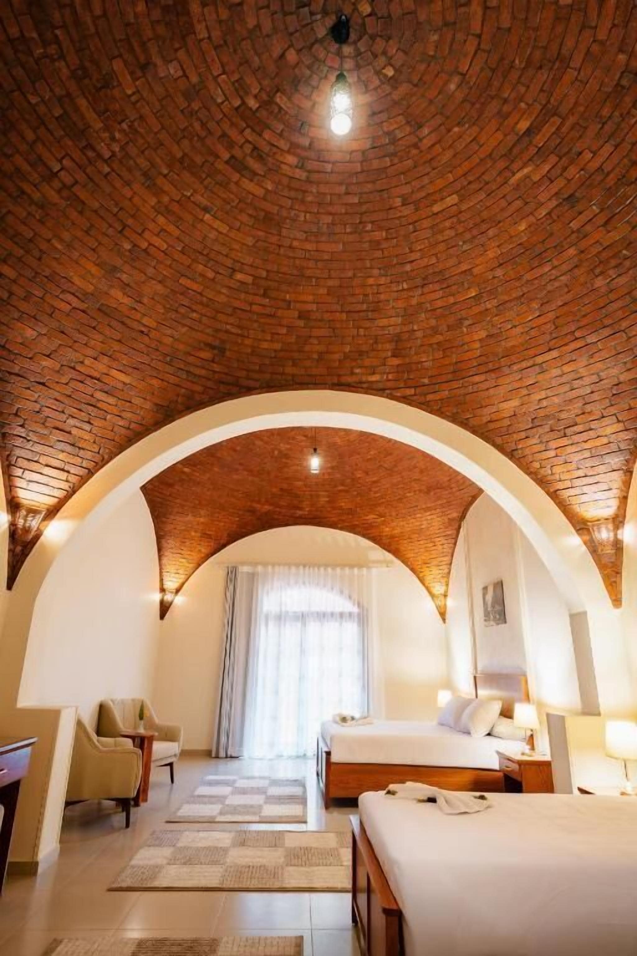 Une pièce avec un plafond en briques, un lit, un bureau et une chaise.