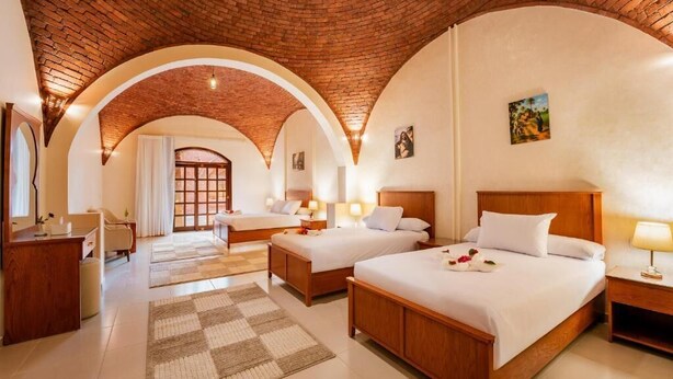 A hotel room with two beds, a desk, a chair, and a large arched brick ceiling. - Opal Legacy Luxor (Luxor)