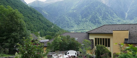 A traditional building with a tiled roof, surrounded by lush greenery and mountains in the background.