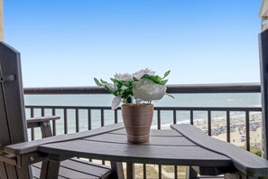 Ein Balkon mit einem Blumentopf und Blick auf den Strand.