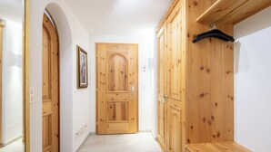 Um corredor com portas de madeira e um banco, um quadro emoldurado na parede e um porta-casacos.
