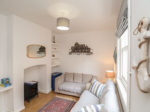 Ein gemütliches Wohnzimmer mit einer Couch, einem kleinen Tisch, einem Kamin und dekorativen Elementen an den Wänden.